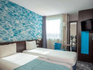 een hotelkamer met 2 bedden en een blauwe muur bij ibis Styles Fontenay in Fontenay-sous-Bois