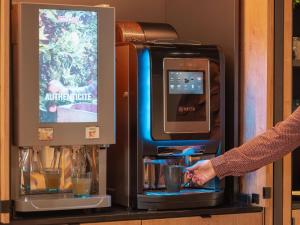 a person is making a drink in a machine at ibis Styles Fontenay in Fontenay-sous-Bois