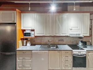 eine Küche mit weißen Schränken, einer Spüle und einer Mikrowelle in der Unterkunft Holiday Home Rukan taikavuosselin helmi 8 b by Interhome in Ruka