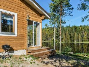 a wooden cabin with a porch and stairs next to a lake at Holiday Home Koskenniska by Interhome in Kortteinen
