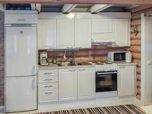 cocina con armarios blancos, fregadero y nevera en Holiday Home Päivärinne by Interhome en Mäkisauru