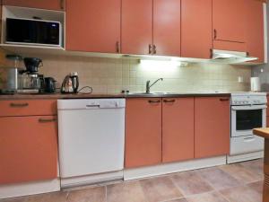a kitchen with orange cabinets and a white dishwasher at Holiday Home Kivikko by Interhome in Laitikkala