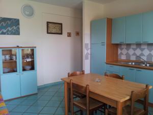 kuchnia z drewnianym stołem i niebieskimi szafkami w obiekcie Residence Oasi Anfiteatro w mieście Porto Ottiolu