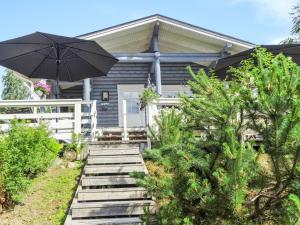 une maison avec une terrasse couverte et un parasol dans l'établissement Holiday Home Käpälysmökki by Interhome, à Nurmes