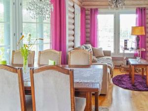 a dining room with a table and pink curtains at Holiday Home Käpälysmökki by Interhome in Nurmes