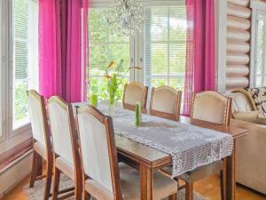 une salle à manger avec une table, des chaises et des rideaux roses dans l'établissement Holiday Home Käpälysmökki by Interhome, à Nurmes