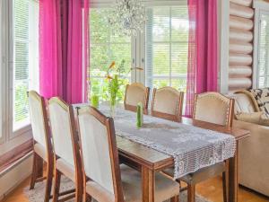 Un comedor con mesa y sillas y cortinas rosas. en Holiday Home Käpälysmökki by Interhome, en Nurmes