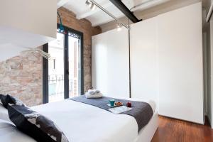 a bedroom with a white bed and a brick wall at AB Paral·lel Apartments in Barcelona