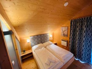 uma pequena cama num quarto com tecto em madeira em Chalet Klippitz - Perle by Interhome em Klippitztorl