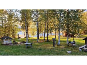 um parque com mesas de piquenique e uma casa e árvores em Holiday Home Koivulahden reinola by Interhome em Raanujärvi
