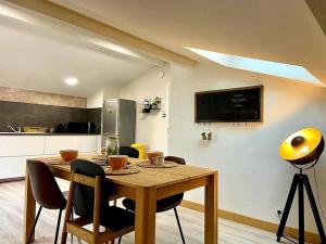 a dining room table with chairs and a kitchen at Cosy au calme, climatisation, 3min A41 in Bernin