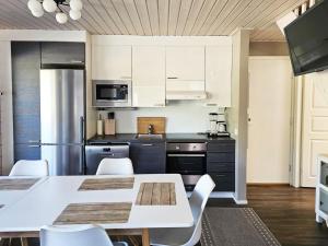 a kitchen with white cabinets and a table and chairs at Holiday Home Himoksen keiju 1 by Interhome in Jämsä