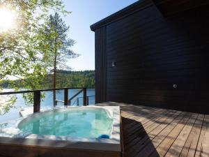 einen Whirlpool auf einer Terrasse mit Blick auf das Wasser in der Unterkunft Holiday Home Villa uggo 4 skipasses included 2024-25 by Interhome in Hyrynsalmi