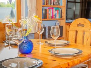 een houten tafel met glazen en borden en een blauwe vaas bij Holiday Home Ferienhaus Bude 87 by Interhome in Bad Arolsen