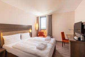 um quarto de hotel com uma cama grande com duas toalhas em IntercityHotel Berlin Airport Area North em Schönefeld