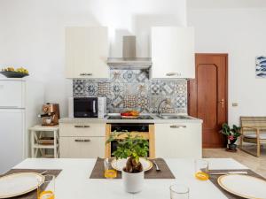サン・ヴィート・ロ・カーポにあるApartment Savoia by Interhomeのキッチン(白い家電製品、テーブル、皿付)