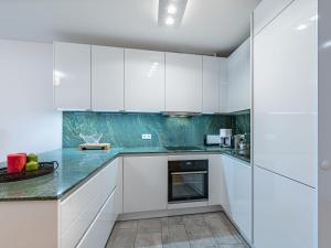 een keuken met witte kasten en groene aanrechtbladen bij Apartment Seeblick alpe maritima Ski & See-Top 12 by Interhome in Annenheim