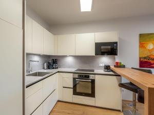 a kitchen with white cabinets and a wooden table at Apartment Terrace 04 alpe maritima Ski & See-Top 4 by Interhome in Annenheim