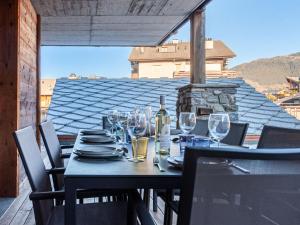 a table with glasses and a bottle of wine on a balcony at Apartment Ferme D'Alice A2 by Interhome in Nendaz