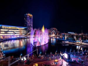 雪梨的住宿－悉尼達令港索菲特酒店，夜水里有一个喷泉的城市