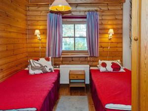 two beds in a room with wooden walls at Holiday Home Sotka 7 by bomba by Interhome in Nurmes
