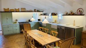 una cocina con mesa de madera y una cocina con armarios verdes en Holiday Home Casa MADORIA, en Sant Climent