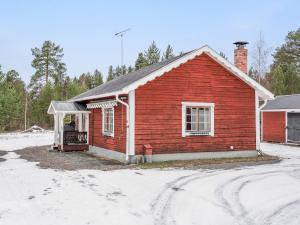 a red building with a porch in the snow at Chalet Norrskensstugan - NBO010 by Interhome in Vidsel