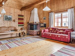 a living room with a red couch and a fireplace at Chalet Norrskensstugan - NBO010 by Interhome in Vidsel