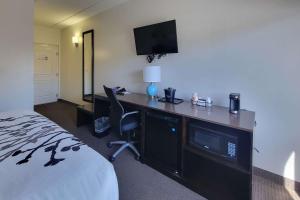 a hotel room with a bed and a desk with a television at Sleep Inn & Suites Panama City Beach in Panama City Beach