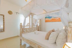 een slaapkamer met een wit bed en een baldakijn bij Fully Furnished 2 Bedroom Apartment along Diani Beach Road in Diani Beach