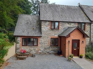 a small brick house with a driveway at Tregib Mill Cottage in Ffair-fâch