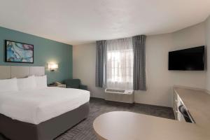 a hotel room with a bed and a flat screen tv at MainStay Suites Raleigh - Cary in Raleigh