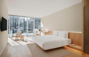 a bedroom with a large white bed and a table and chairs at Commune by the Great Wall, in the Unbound Collection by Hyatt in Yanqing