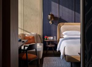 南京市にあるAndaz Nanjing Hexiのベッド、椅子、テーブルが備わるホテルルームです。