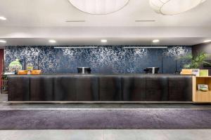 a reception desk in a lobby with a blue wall at Vienna House Easy by Wyndham Bucharest Airport in Otopeni