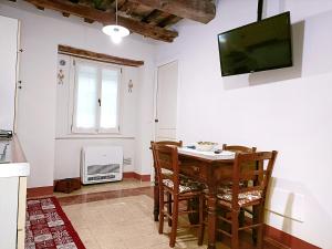 een keuken met een tafel en stoelen en een televisie bij Casa rustica tra mare e collina in Morciano di Romagna