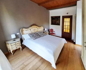 una camera con un grande letto bianco e un pavimento in legno di Casa Martini a Pecetto
