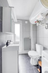 La salle de bains blanche est pourvue de toilettes et d'un lavabo. dans l'établissement Studio lumineux Maisons-Laffitte, à Maisons-Laffitte