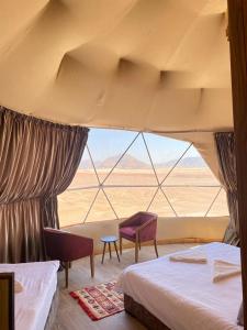 a bedroom with two beds and a view of the desert at wadi rum Milky Way Camp in Disah