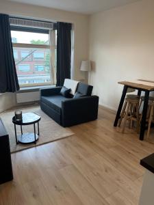 a living room with a black couch and a table at Cosy Apartment in the Hague! in The Hague