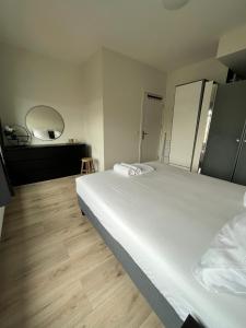a bedroom with a large white bed and a mirror at Cosy Apartment in the Hague! in The Hague