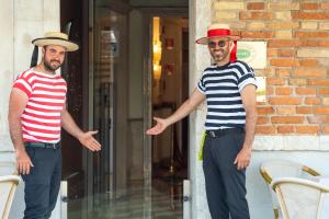 two men wearing hats standing outside of a building at Hotel Antiche Figure in Venice
