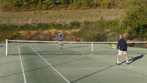 two people playing tennis on a tennis court at Panorama Gîtes Certes in Gaudiès