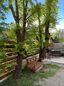 a wooden bench sitting next to two trees at House in El Chalten