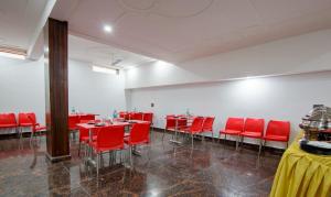 a dining room with red chairs and tables in a room at Hotel Grand Vista in Noida