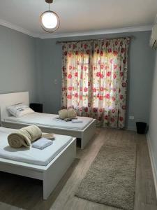 1 dormitorio con 2 camas y una ventana con flores en 2 Bedroom Flat in Elrehab Cairo شقه رائعه من غرفتين نوم بالرحاب, en El Cairo