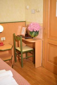 uma secretária com um vaso de flores cor-de-rosa e uma cadeira em Hotel Baffo Rosso em Alba Adriatica