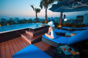 a woman sitting on a bench next to a swimming pool at Alagon City Hotel & Spa in Ho Chi Minh City