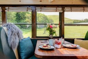a table with plates of food and flowers on it at Skoolie Stays - Luxury American school bus conversion in Storrington