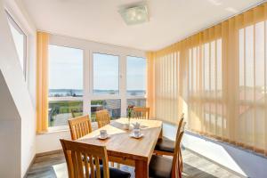 une salle à manger avec une table, des chaises et des fenêtres dans l'établissement Peenemünde, Seglerhafen SB Brig 09,15, à Peenemünde 9 autres photos